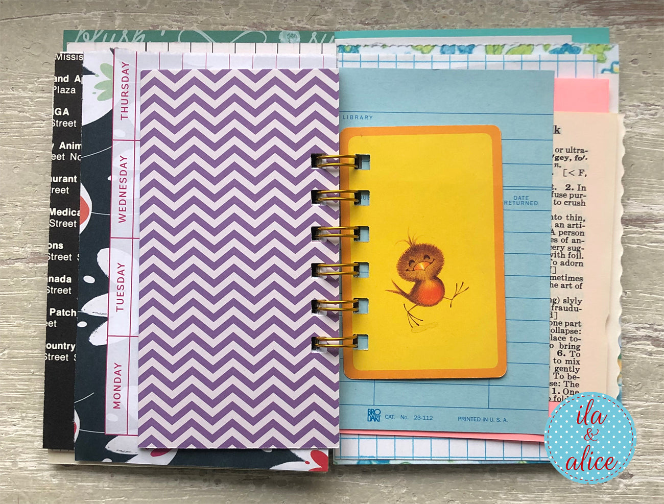 Collection of planners with different designs on a wooden surface, featuring a brand logo in the corner.