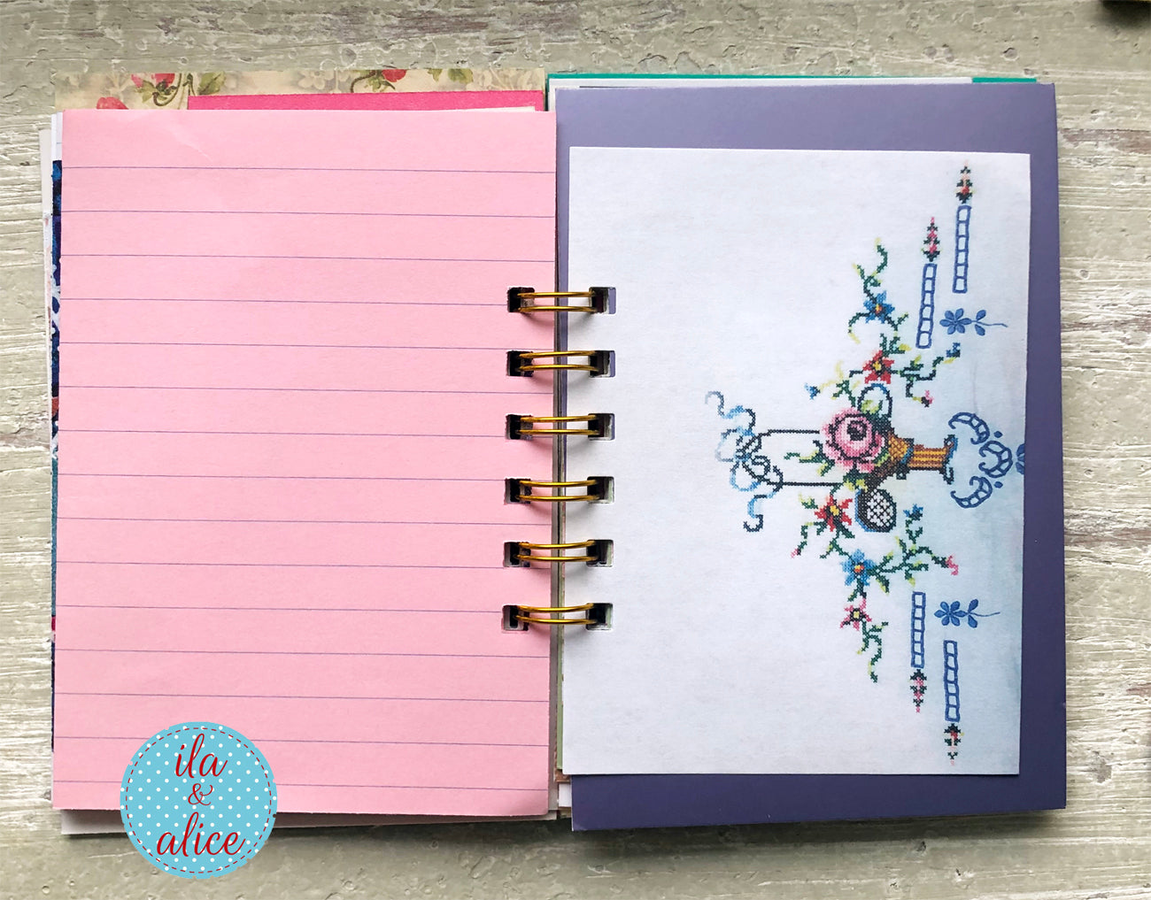 Open planner with pink interior pages and floral design on a wooden surface