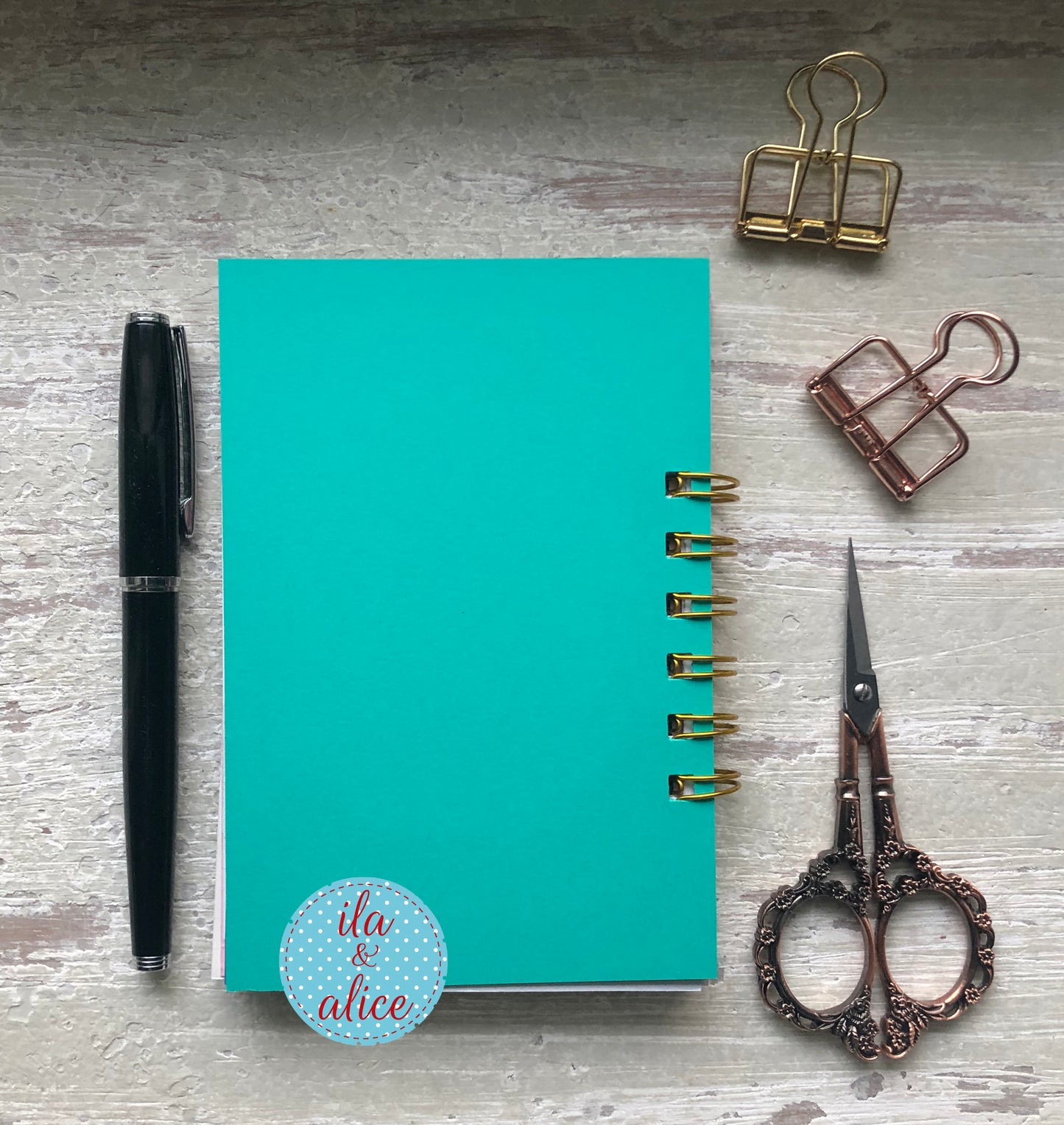 Turquoise notebook with decorative elements on a wooden surface