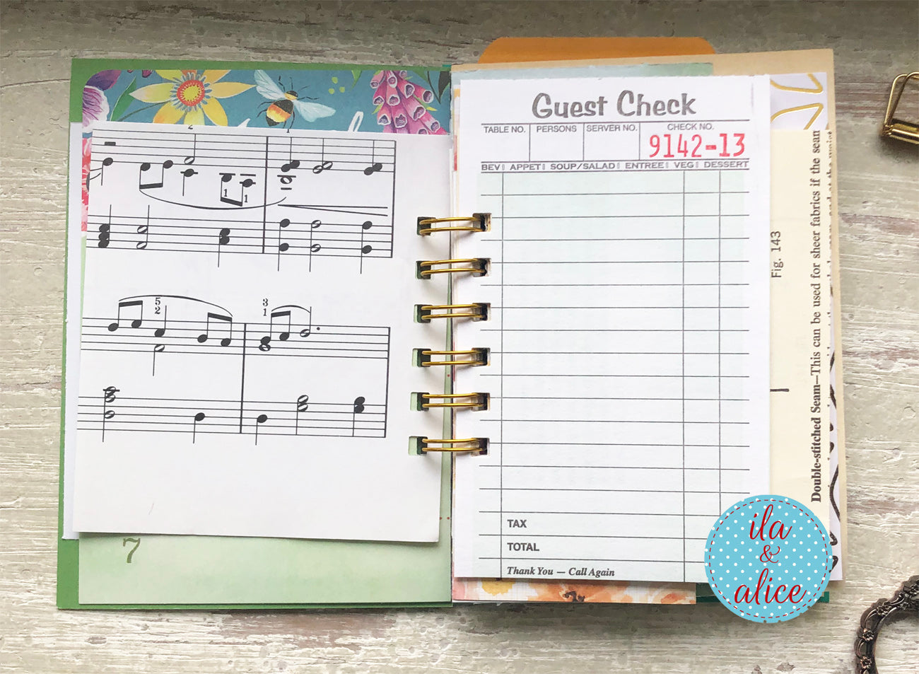 Planner with music sheet and guest check pages on a wooden surface, featuring the brand 'ila & alice'.
