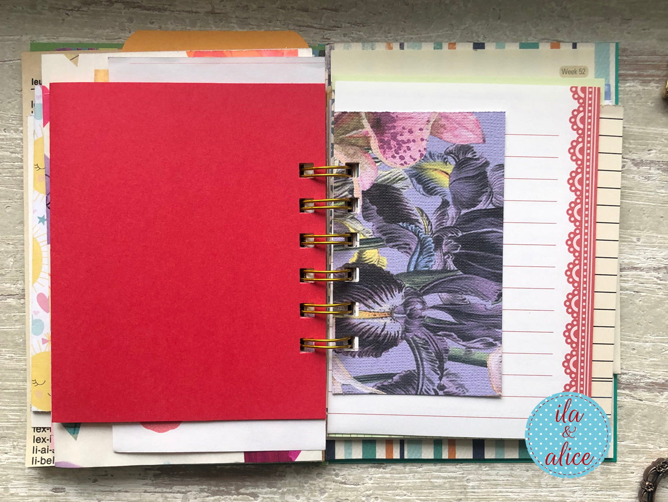 Planner with colourful pages and a red cover on a wooden surface, featuring the brand 'ila & alice'.